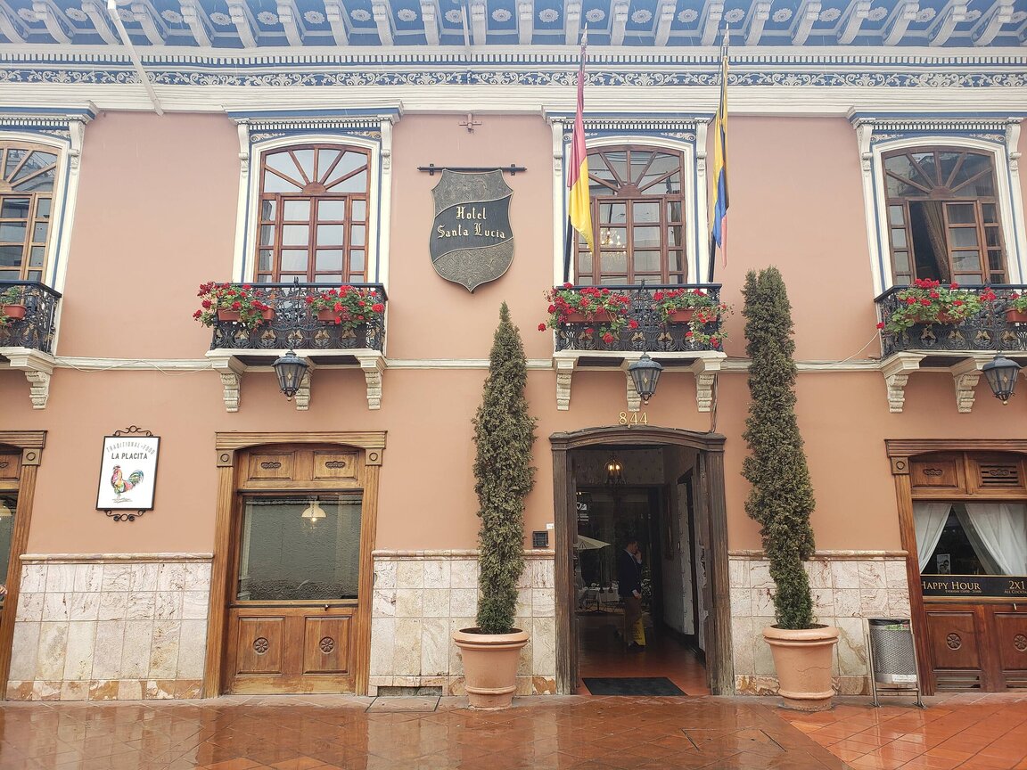 Außenansicht des Hotel Santa Lucia in Cuenca, Ecuador mit historischer Fassade, verzierten Fenstern, Blumenkästen und kolonialem Charme.