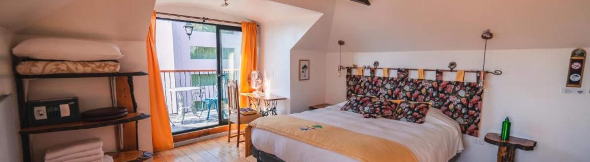 Schlafzimmer im Dachgeschoss mit Holzbalken, Doppelbett und Balkonzugang in Valparaiso.