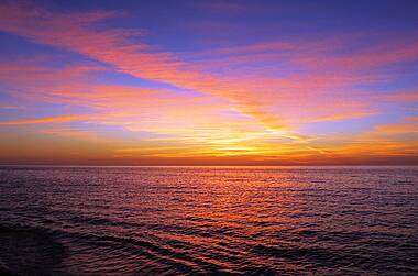 Sonnenuntergang über rotblau erleuchtetem Meer in Celestun