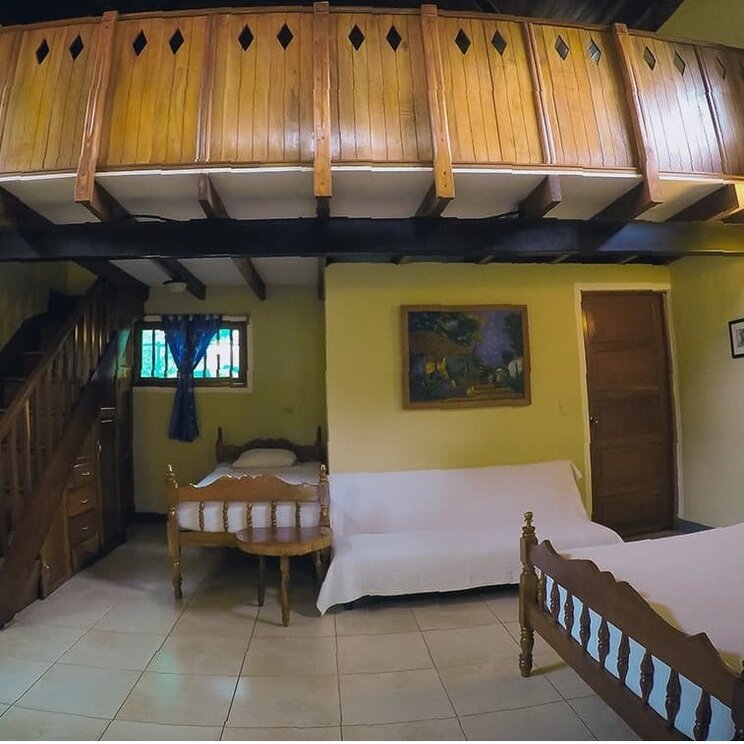 Etagenzimmer im Hotel Villa Paraíso auf der Insel Ometepe, Nicaragua, mit großem Holzbett, hellen Wänden.