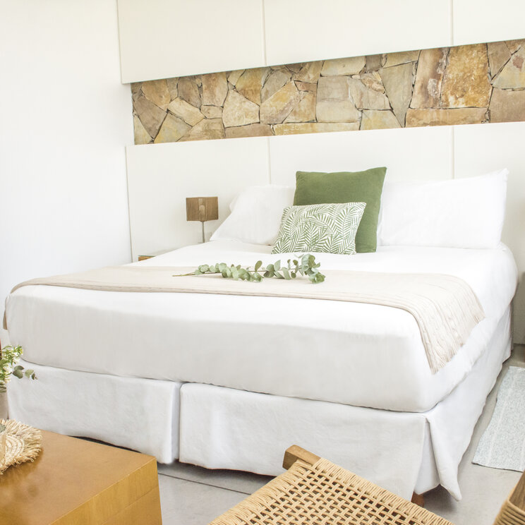 Hell eingerichtetes Doppelzimmer im Mine Hotel in Buenos Aires mit Kingsize-Bett und einer Steinwand-Applikation.