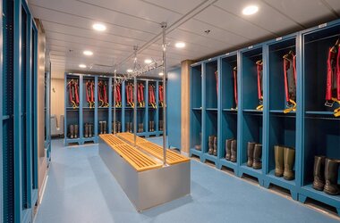 Der moderne Mudroom der Ocean Albatros mit Schließfächern, Expeditionsstiefeln und bereitstehenden Schwimmwesten für die Landgänge auf der Antarktis-Kreuzfahrt