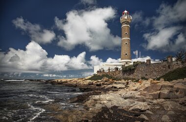 Ein Leuchtturm in José Ignacio, Uruguay, steht auf einer felsigen Küste unter einem blauen, bewölkten Himmel