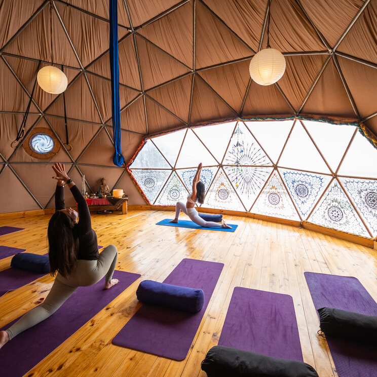 Yoga-Dom im EcoCamp Patagonia im Torres del Paine Nationalpark mit Teilnehmern auf Matten und Panoramafenstern mit Blick in die Natur.