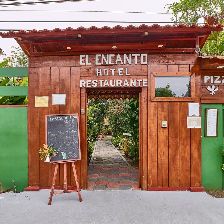 Hoelzernes Eingangstor zum Hotel mit Hinweisschildern in Costa Rica.