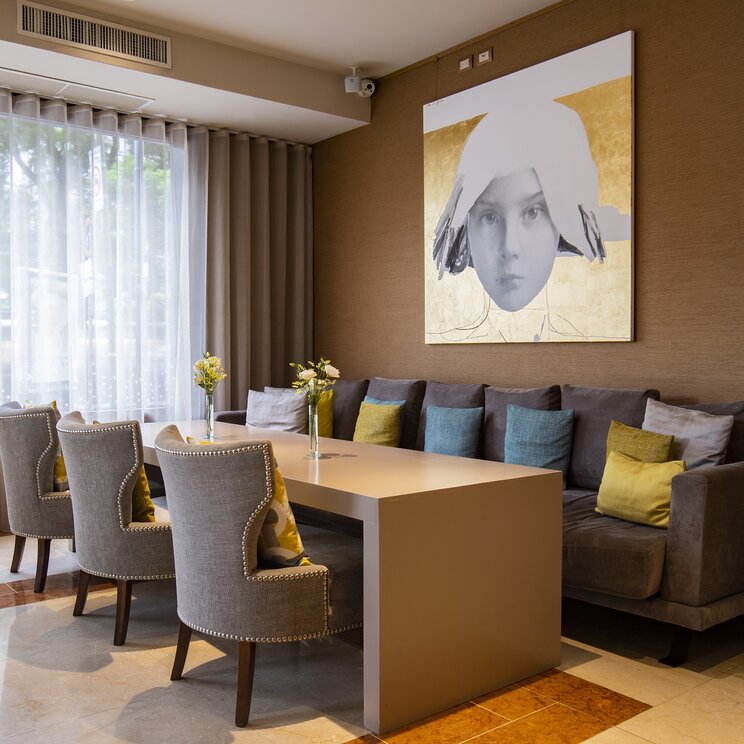 Sitzbereich im Restaurant mit langem Tisch, Polstersesseln, Sofa und modernem Portraetgemaelde in Buenos Aires.