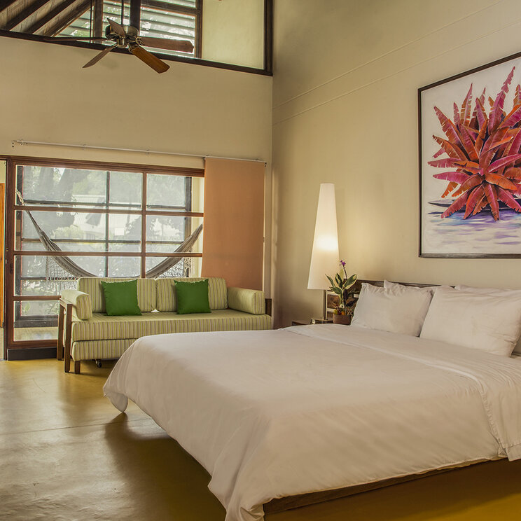 Standardzimmer mit Doppelbett, Gemaelde und Blick auf Haengematte im Hotel Decameron Decalodge Ticuna in Leticia.