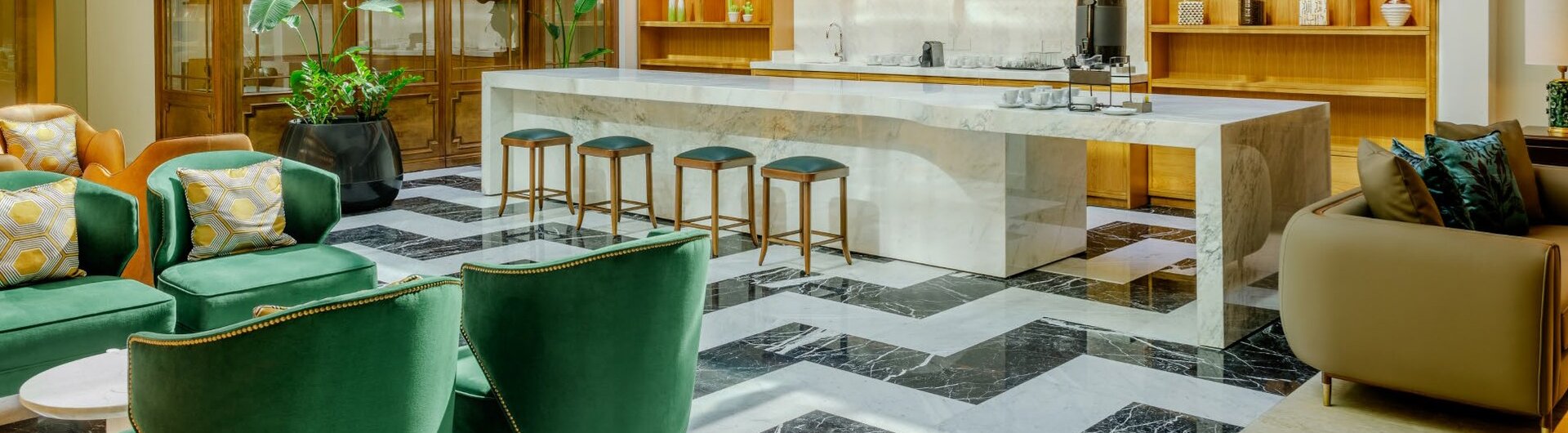 Cafebar im Recoleta Grand Buenos Aires mit Marmortresen, Glasdach, Holzregalen und gruenen Sesseln auf Fliesenboden.