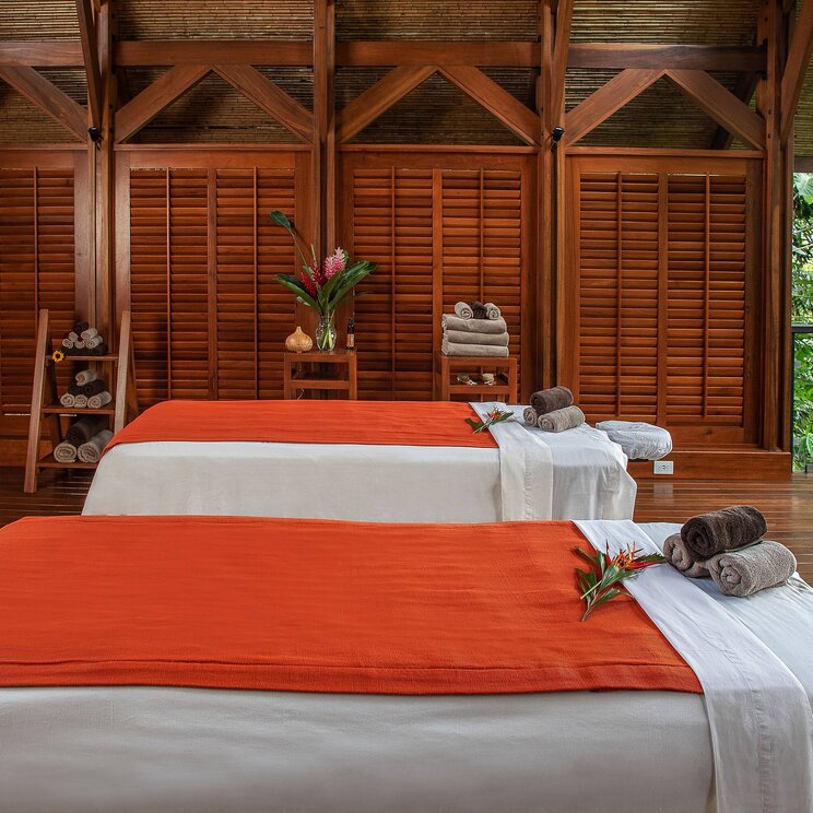 Spa-Bereich im Hotel Amor Arenal in La Fortuna, Costa Rica, mit zwei Massageliegen in offener Holzstruktur und Blick ins tropische Grün.