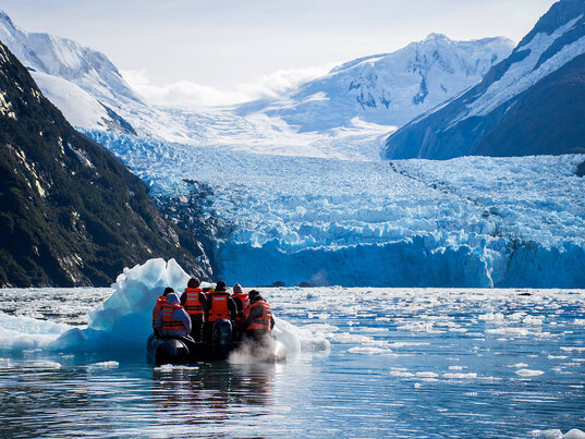 Touristen im Schlauchboot der Cruceros Australis vor einem gewaltigen Gletscher auf Feuerland.