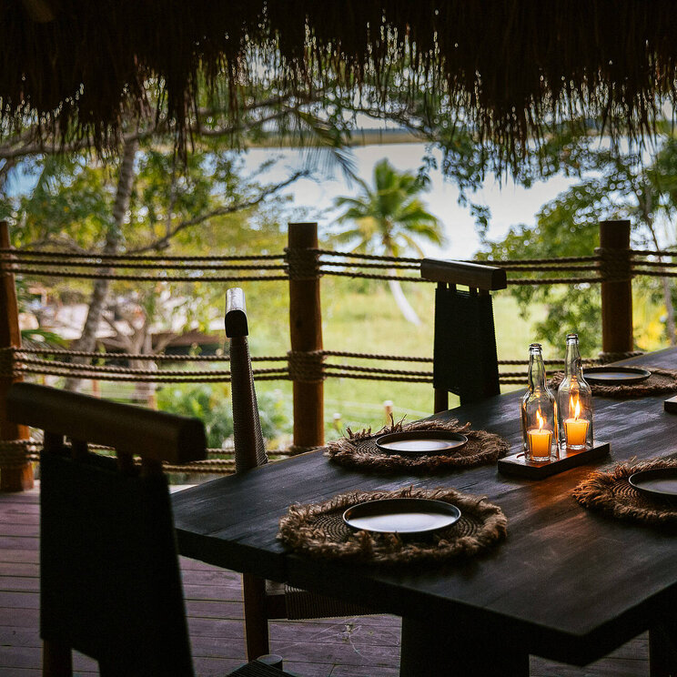 Stimmungsvoll gedeckter Tisch im Hotel Our Habitas Bacalar mit Kerzenlicht und Blick ins Grüne.
