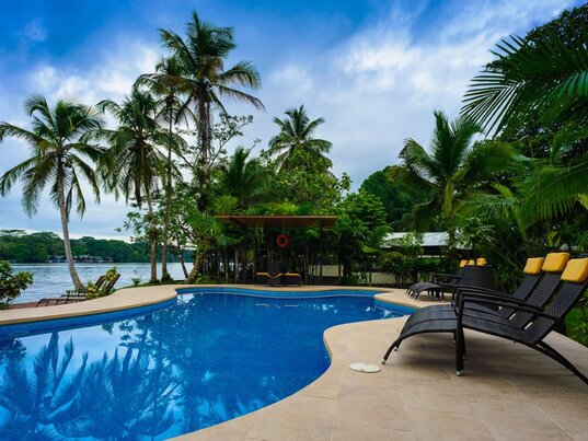 Poolbereich im Manatus Hotel in Tortuguero, Costa Rica, umgeben von Palmen und tropischer Vegetation.