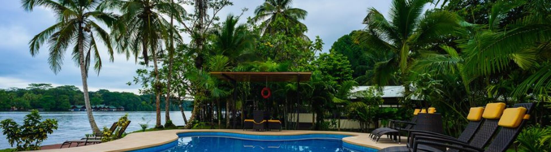 Poolbereich im Manatus Hotel in Tortuguero, Costa Rica, umgeben von Palmen und tropischer Vegetation.