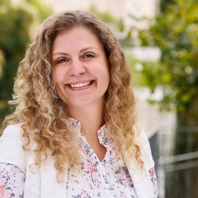 Giselle Beyer Thó, Mitarbeiterin bei Gateway Lateinamerika, steht lächelnd auf einer Brücke mit grünem Flussufer im Hintergrund.