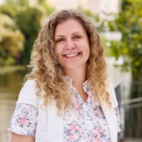 Giselle Beyer Thó, Mitarbeiterin bei Gateway Lateinamerika, steht lächelnd auf einer Brücke mit grünem Flussufer im Hintergrund.