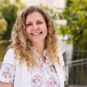 Giselle Beyer Thó, Mitarbeiterin bei Gateway Lateinamerika, steht lächelnd auf einer Brücke mit grünem Flussufer im Hintergrund.