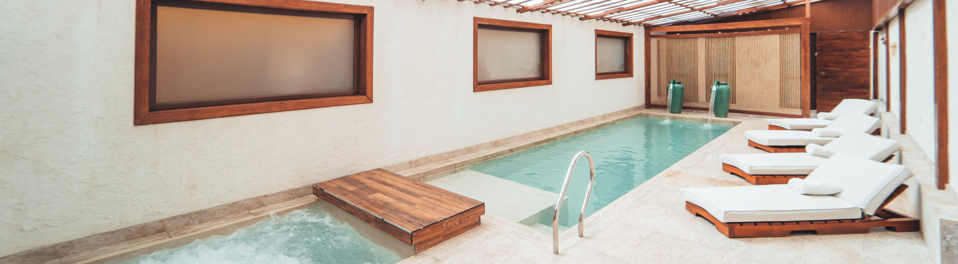 Hallenbad mit Whirlpool, Liegestühlen und Landschaftsbildern an der Wand im Hotel Jardines de Uyuni in Bolivien.