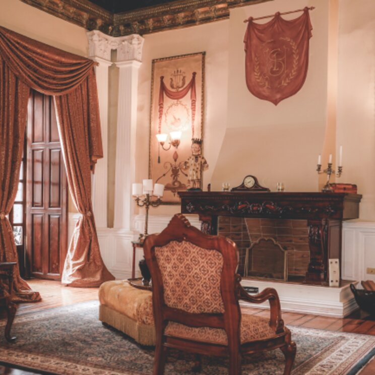 Historischer Salon im Hotel Santa Lucia in Ecuador mit opulenter Einrichtung, Kamin, antiken Möbeln und aufwendig dekorierten Wandteppichen.