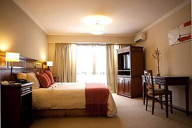 Zimmer mit Doppelbett und dunklen Möbeln im Hotel Aires de Salta