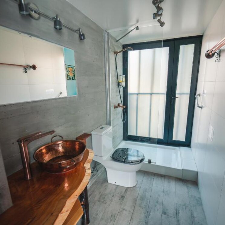 Badezimmer mit Kupferwaschbecken auf Naturholzplatte und moderner Dusche in Valparaiso.