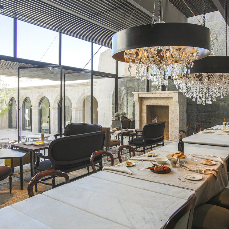 Moderner Speisesaal mit grossen Glasfronten, Kristallleuchtern und Marmortischen im CIRQA Hotel Arequipa.