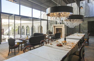 Moderner Speisesaal mit grossen Glasfronten, Kristallleuchtern und Marmortischen im CIRQA Hotel Arequipa.