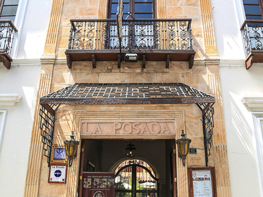 Hoteleingang vom Boutique Hotel La Posada in Sucre mit Steinfassade, Balkon und schmiedeeisernem Tor.