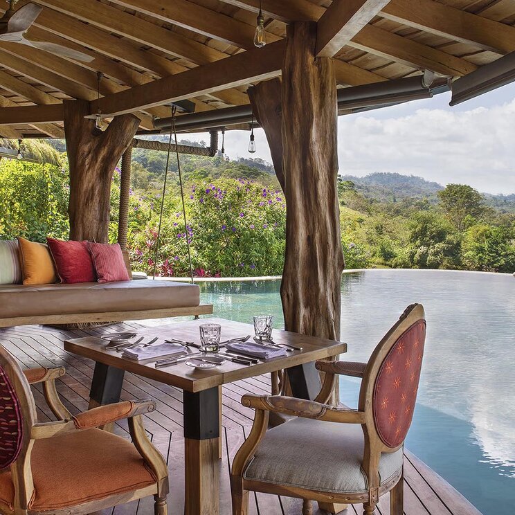 Restaurantbereich der Origins Luxury Lodge in Costa Rica mit Blick auf den Infinity-Pool und die umliegende Natur.
