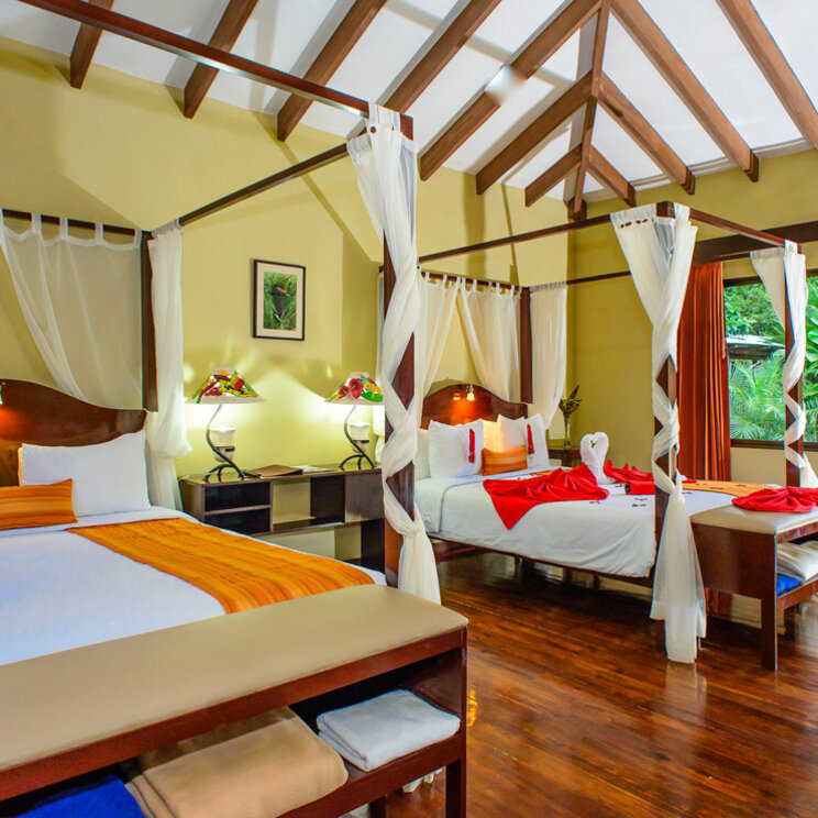 Zimmer im Manatus Hotel in Tortuguero, Costa Rica, mit zwei Betten, Holzboden und Aussicht auf die tropische Umgebung.