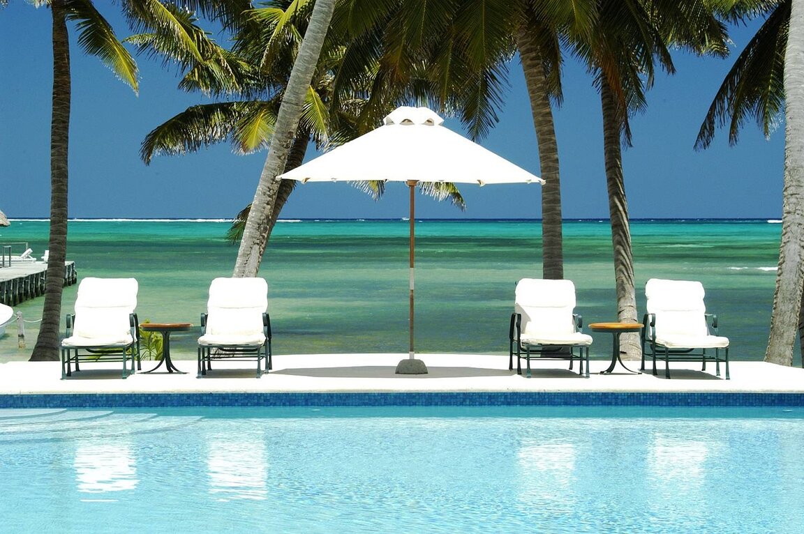 Pool mit Sonnenschirm und Liegestühlen auf Ambergris Caye