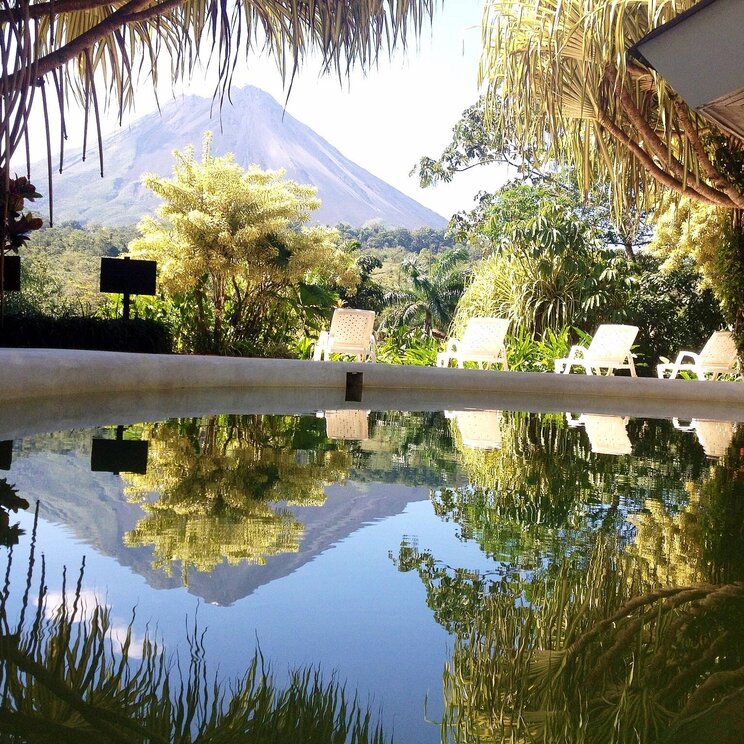 Pool im Hotel Arenal Paraíso Resort & Spa in La Fortuna, Costa Rica, mit Blick auf den Vulkan Arenal und umgeben von tropischer Vegetation.
