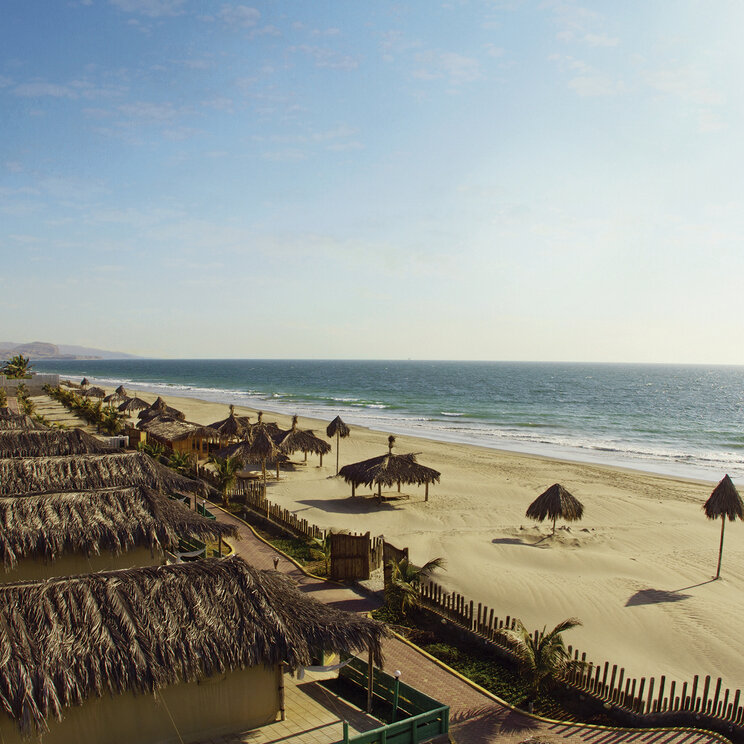 Aranwa: Strandbungalows mit Strohdächern an einer weitläufigen, menschenleeren Pazifikküste.