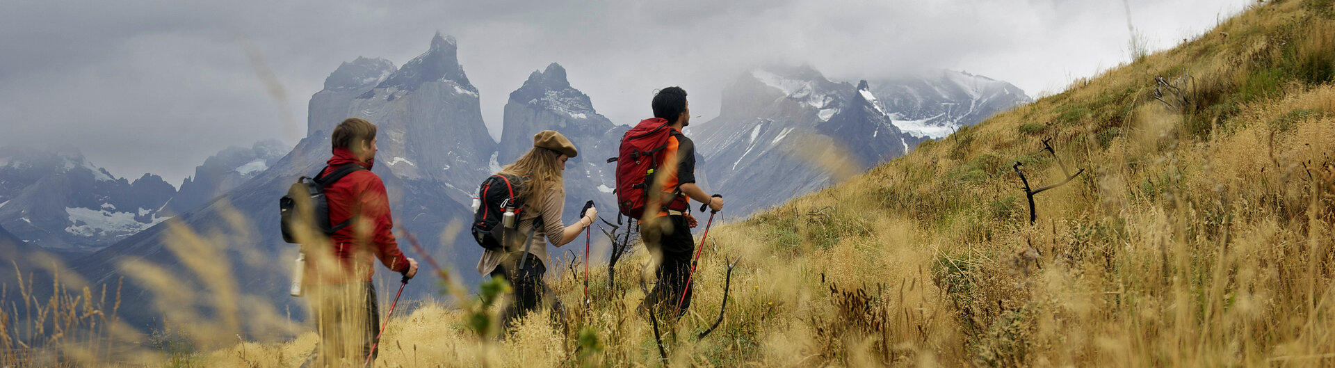 Ein Wanderer mit Rucksack blickt auf einem Pfad im Nationalpark Torres del Paine auf die fernen Felsgipfel.