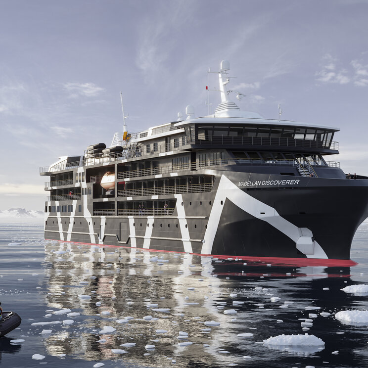 Das moderne Expeditionsschiff Magellan Discoverer fährt durch das ruhige, von Eisbergen durchsetzte Meer in der Antarktis, während im Vordergrund Passagiere in einem Zodiac-Schlauchboot unterwegs sind.
