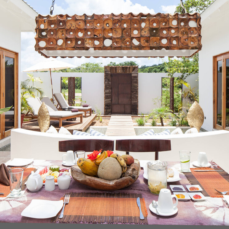 Frühstückstisch im Ka'ana Resort in San Ignacio, Belize mit Blick auf eine stilvolle Terrasse und gemütliche Sonnenliegen.