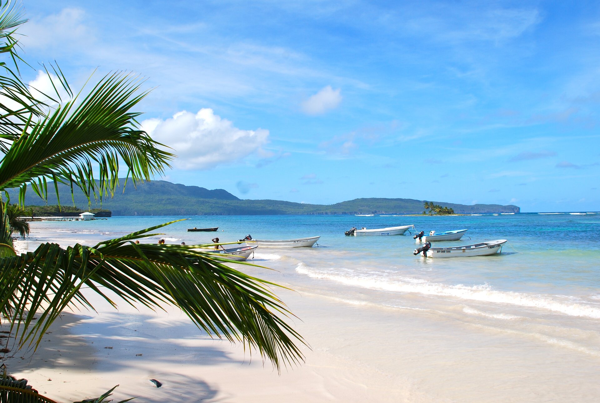 Strand von Las Galeras in der Dominikanischen Republik mit weißen Sandstränden, Fischerbooten und Blick auf das türkisfarbene Meer.