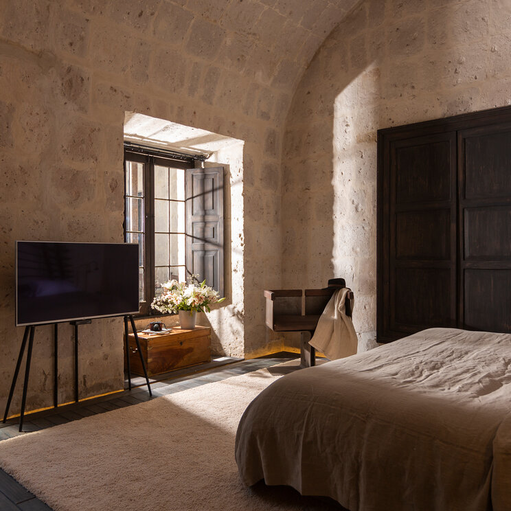 Hotelzimmer mit tiefen Fensternischen, dunklen Fensterlaeden und Sillar-Steinmauerwerk im CIRQA Arequipa.