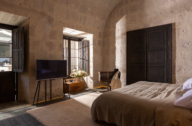 Hotelzimmer mit tiefen Fensternischen, dunklen Fensterlaeden und Sillar-Steinmauerwerk im CIRQA Arequipa.