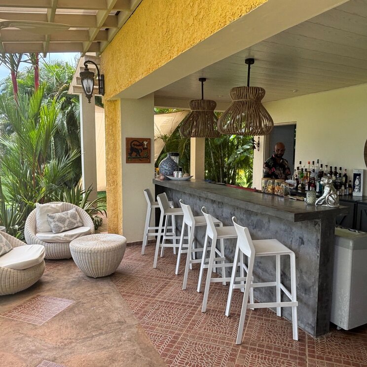 Überdachte Außenbar mit Betontresen, Barhockern, Korbsesseln und Palmen in Boca Chica, Panama.