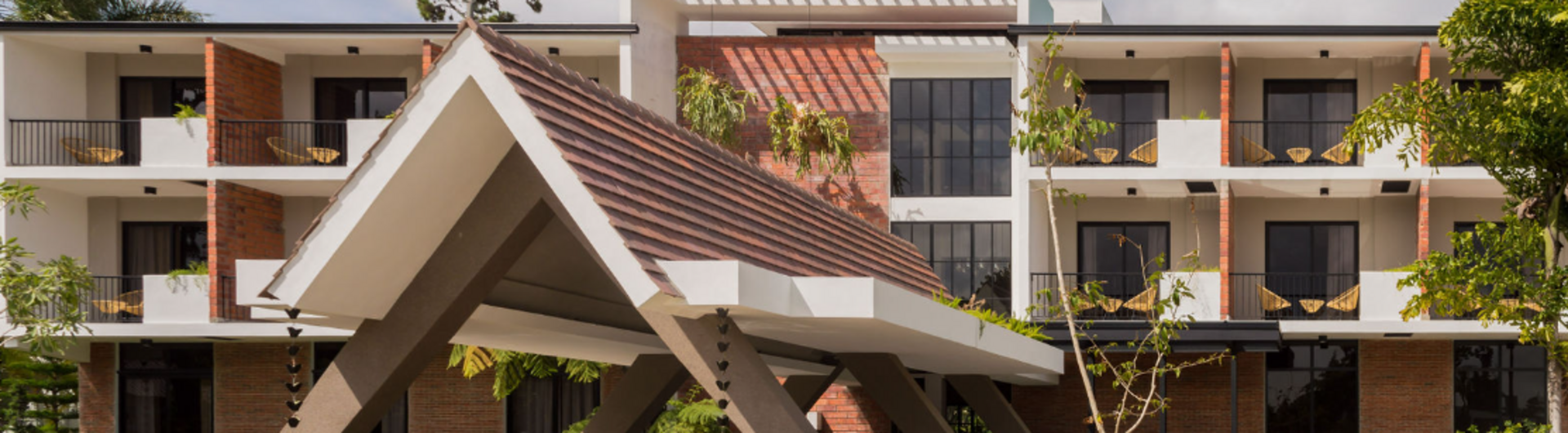Außenansicht des Hotel Pinar Dorado in Jarabacoa, Dominikanische Republik, mit moderner Architektur, markantem Eingangsbereich und Balkonzimmern mit Hängematten.