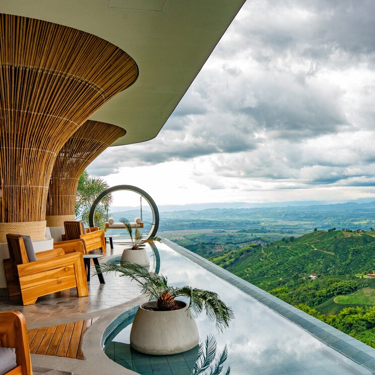 Ueberdachte Terrasse mit markanten Bambussaeulen und Panorama-Aussicht auf das Tal.