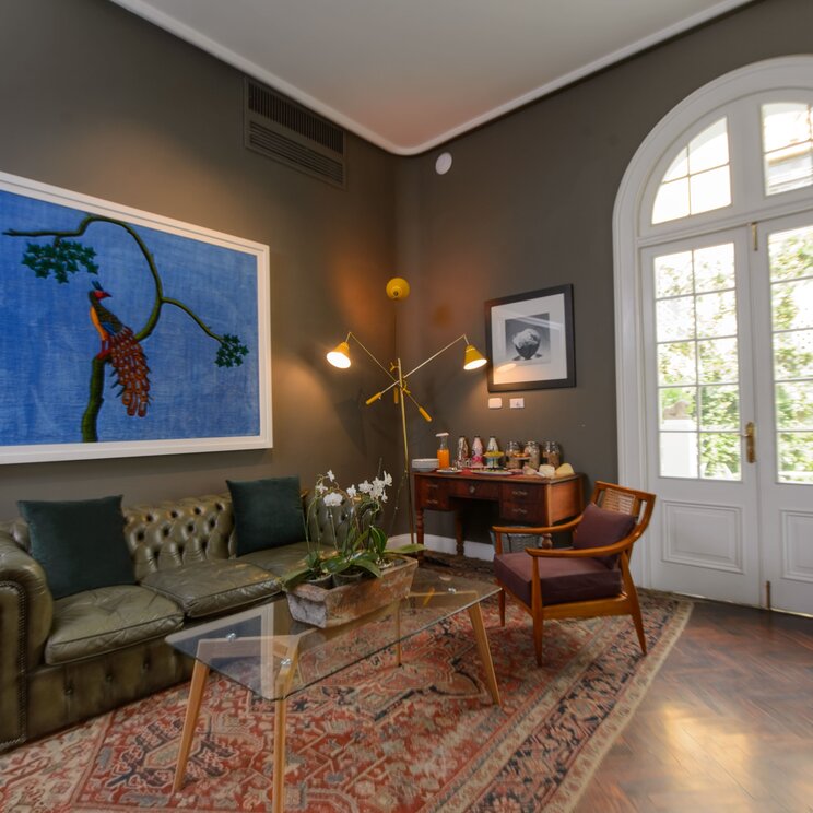 Salon mit Ledersofa, Gabeltisch, Teppich, Gemälde und Flügeltuer im Hotel Villa Barranco in Lima, Peru.