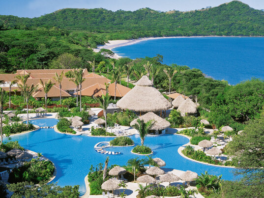 Tropische Poollandschaft des Hotels The Westin Playa Conchal in Costa Rica mit Blick auf die Bucht und umliegenden Wald.