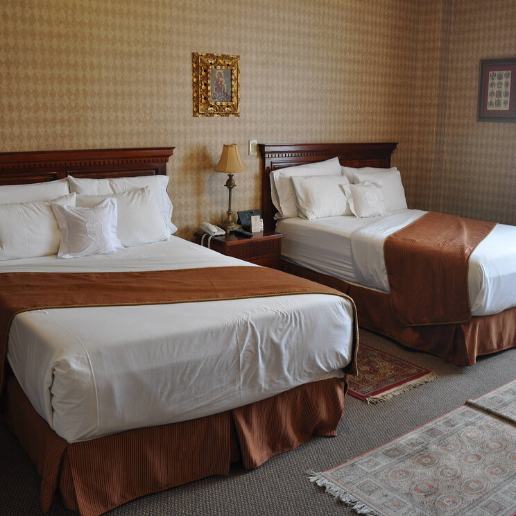 Zimmer im Hotel Santa Lucia in Ecuador mit zwei großzügigen Betten, klassischem Mobiliar und eleganter, warm getönter Wandgestaltung.