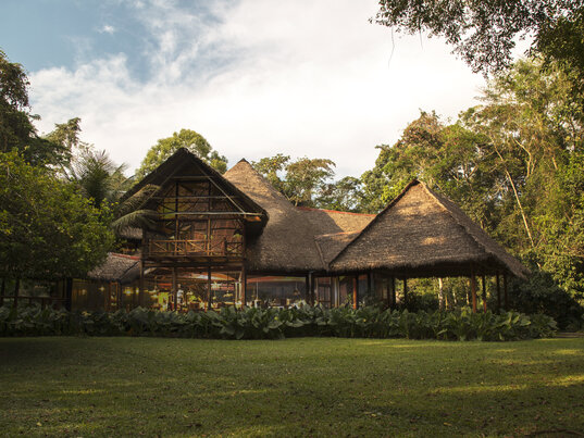 Zweistoeckiges Haupthaus mit Strohdach inmitten von Regenwald in Puerto Maldonado, Peru.