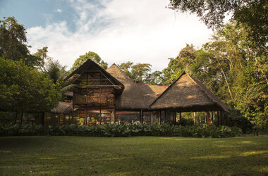 Zweistoeckiges Haupthaus mit Strohdach inmitten von Regenwald in Puerto Maldonado, Peru.