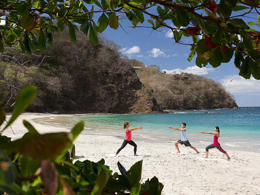 3 Personen praktizieren Yoga am Meer in Costa Rica