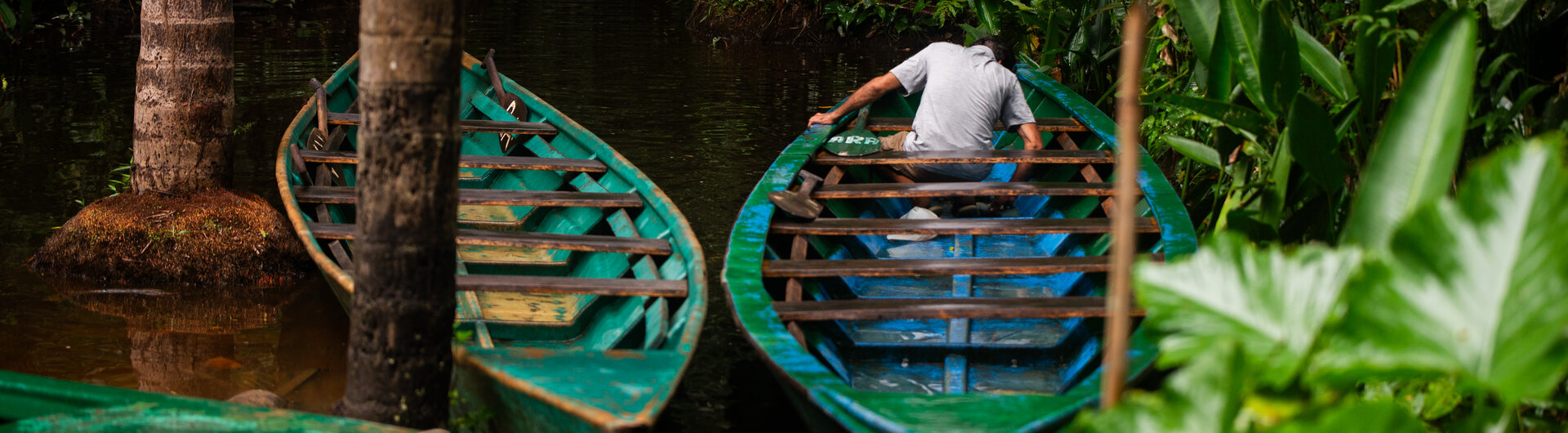 Mann in Holzboot auf einem Fluss im Dschungel bei Inkaterra Hacienda Concepcion in Puerto Maldonado, Peru.