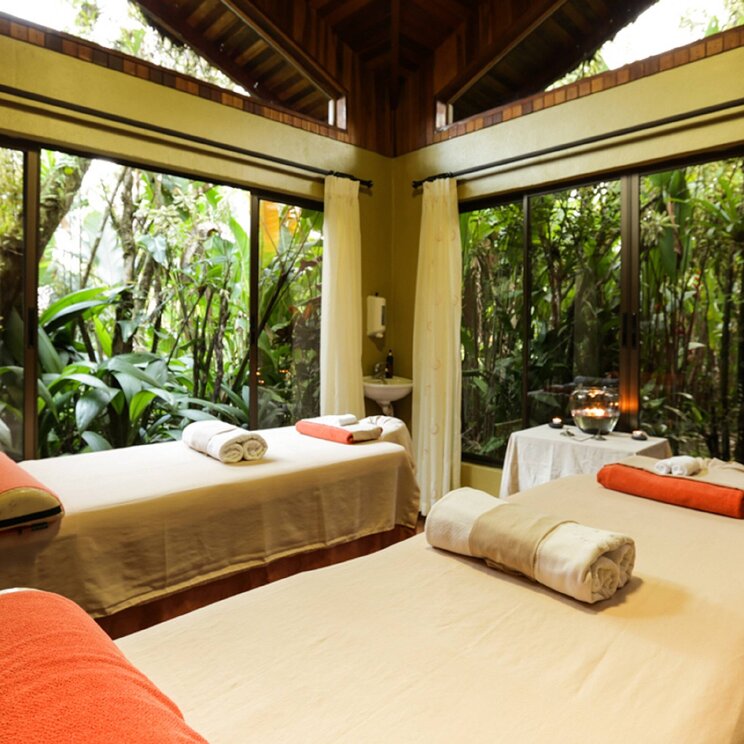 Spa-Bereich im Hotel Arenal Paraíso Resort & Spa in La Fortuna, Costa Rica mit zwei Massagebetten und Blick ins tropische Grün.