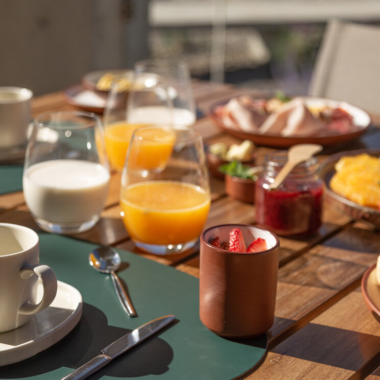 Gedeckter Frühstückstisch im Freien mit Croissants, Orangensaft, Kaffee und Früchten in Argentinien.